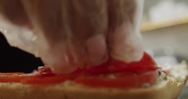 Девушка делает сэндвич с салями. Подает помидоры на хлеб. Медленное движение — стоковое видео