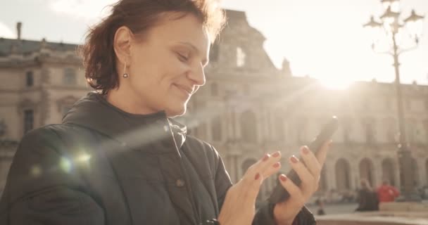 Kvinnan ser ut och fotograferar med telefonkamera på solig dag i gamla stan. Närbild skott — Stockvideo
