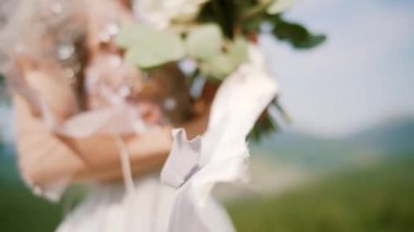 Gelinler elinde buket, kurdeleler rüzgarda açılır. Ağır çekim. Kapat.
