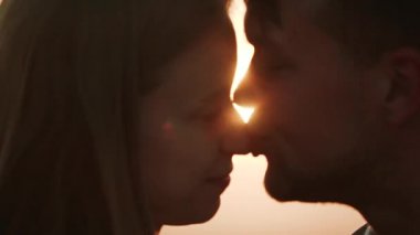 Birbirine aşık çiftler, karlı yamaçlarda duran bir buket çiçeği tutarlar. Arkalarında portakal rengi gün batımını resmederler. Birbirlerini öpüp dağlık araziyi sisle kaplarlar.