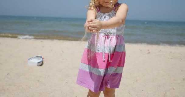 Entzückendes kleines Mädchen am Strand. Glücklich Mädchen spielen mit Sand Zeitlupe — Stockvideo