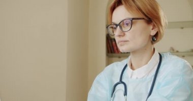 Masada oturan kadın doktor dizüstü bilgisayarda çalışıyor. Ağır çekim. Kamerayı taşı
