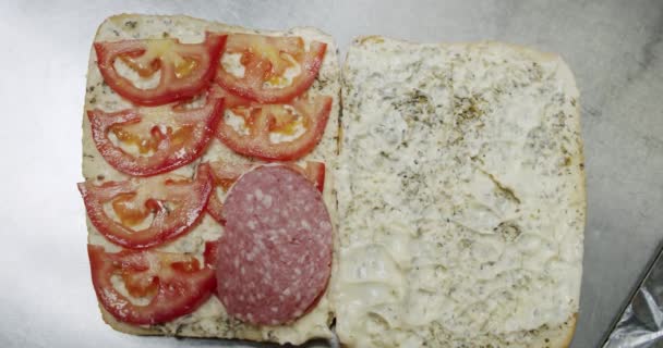 Sandwich met salami. Zet worst op brood. Langzame beweging Bovenaanzicht — Stockvideo