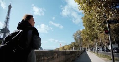 Sırt çantalı turist kadınlar Eiffel Kulesi ve Seine Nehri 'nin yanından geçerek akıllı telefondan fotoğraf çekiyorlar. Geniş açı