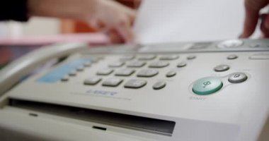 Faksı kullanan bir kadının eli, faks mesajı alıyor, kapatıyor.