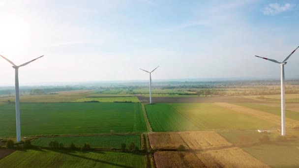 Вид с аэродрона. Ветряные турбины и сельскохозяйственные поля в летний день с лучами солнца — стоковое видео