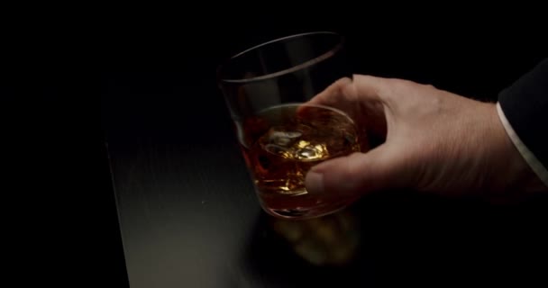 人の手はウイスキーと氷のガラスを取る。スローモーションを閉じます — ストック動画