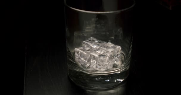 Slow motion gyllene whisky häller i glaset med isbitar från flaskan. Närbild V4 — Stockvideo