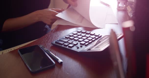 Close up woman hands of with a calculator counts checks with the suns rays — Stock Video