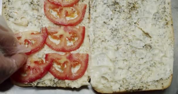 Een meisje met salami. Zet tomaat op brood. Langzame beweging Bovenaanzicht — Stockvideo