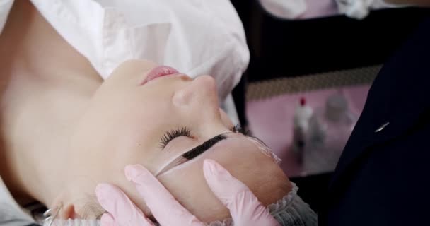 The cosmetologist begins the procedure correction the shape of eyebrows in a beauty parlor. A method of eyebrow correction with powder spraying. Microblading, eyebrow tattoo,. Slow motion. Close up — Stock Video
