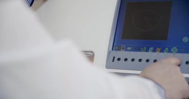 Gözlük yapıyor, objektifi optik mağazada gözlük takmak için makine öğütücüsüne takıyor ve lensleri buduyor.