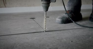 İşçi ısı yalıtımlı bir zemin için delik açıyor. Kapat.