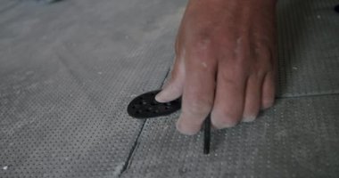 İşçi, ısı yalıtımlı zeminin elementlerini kıskaçlarla tamir eder.