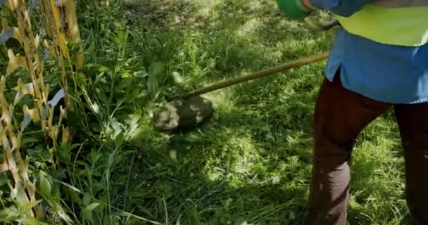 Arbetaren klipper gräset på gräsmattan med en bensingräsklippare, slow motion Midlr skott — Stockvideo