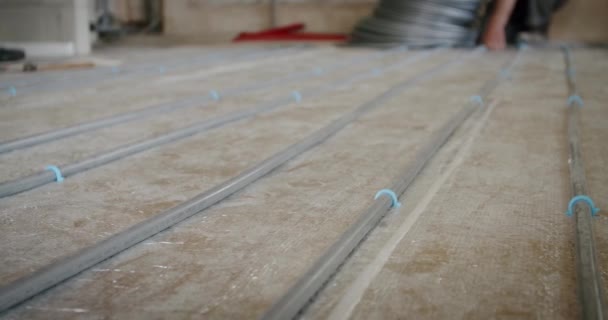 Tangan pekerja memperbaiki tabung untuk lantai yang dipanaskan. Tutup. — Stok Video