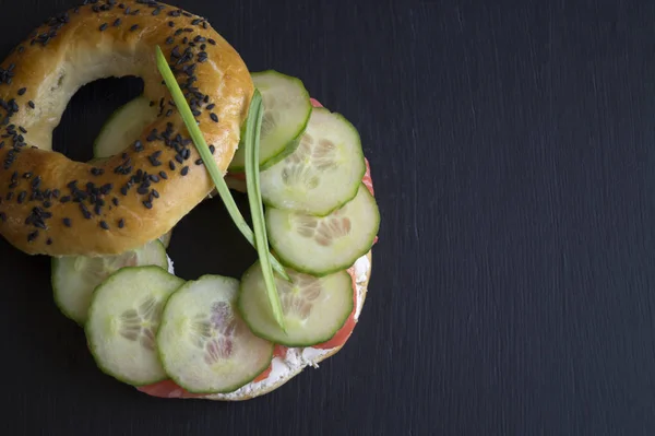 Bagels com sementes de gergelim em um fundo preto — Fotografia de Stock