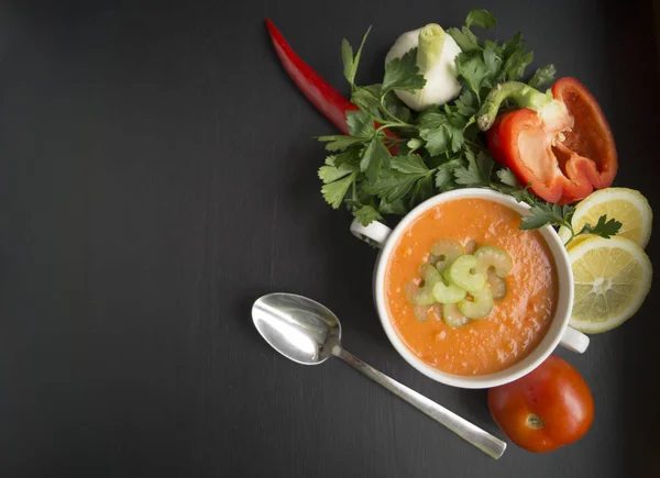 Томатный суп с овощами и зеленью на черном фоне — стоковое фото
