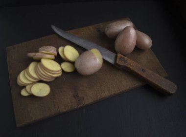 Çiğ patates bir kesme tahtası üzerinde - dilimlenmiş pişirme