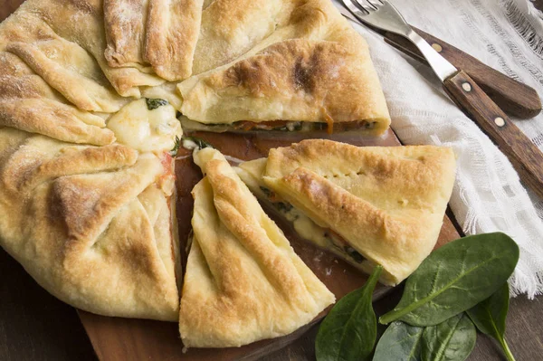 Torta di pasta sfoglia con spinaci su una tavola di legno — Foto Stock