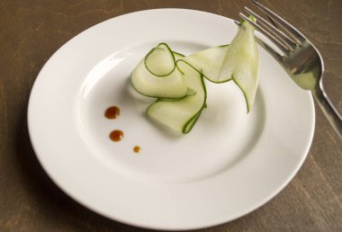 ince dilimlenmiş salatalık beyaz bir plaka üzerinde