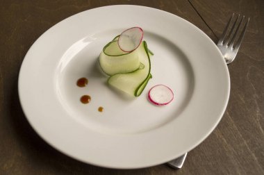 ince dilimlenmiş salatalık beyaz bir plaka üzerinde