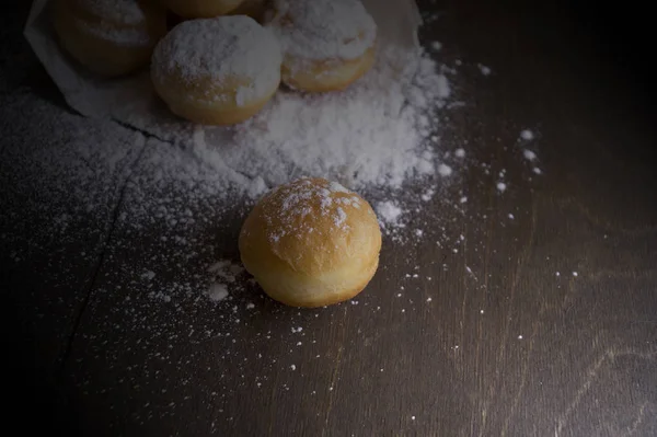 Round donuts in a paper bag sprinkled with powder — Stock Photo, Image