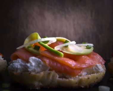 Simit krem peynir ve siyah bir arka plan üzerinde füme somon ile