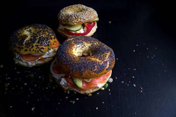 Füstölt lazac egy fekete háttér és a krémsajt bagel — Stock Fotó