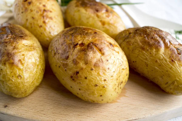 Pikantní pečené brambory na dřevěné desce, closeup — Stock fotografie