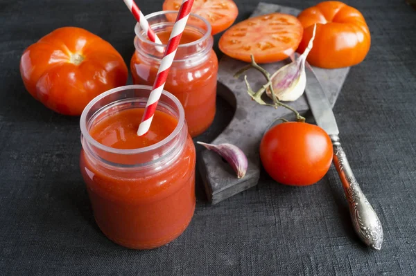 Suco de tomate em um frasco na mesa preta — Fotografia de Stock