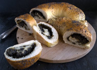 Haşhaşlı rulo, ahşap oyun tahtası, siyah bir zemin üzerine dilimlenmiş