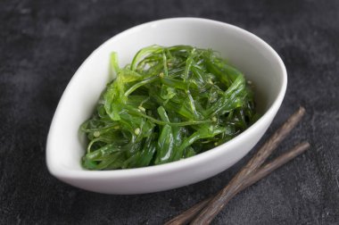 Japon yemek çubukları ile seramik kase yosun salata.