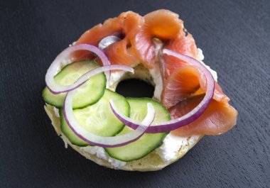 Simit krem peynir ve siyah bir arka plan üzerinde füme somon ile