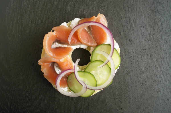 Bagels com creme de queijo e salmão defumado em um fundo preto — Fotografia de Stock