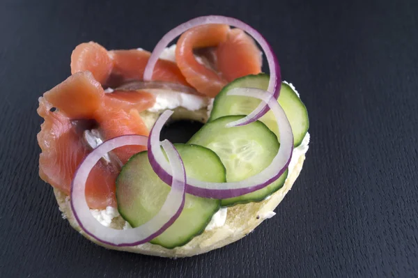 Simit krem peynir ve siyah bir arka plan üzerinde füme somon ile