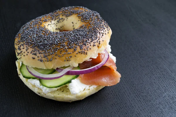 Bagels com creme de queijo e salmão defumado em um fundo preto — Fotografia de Stock