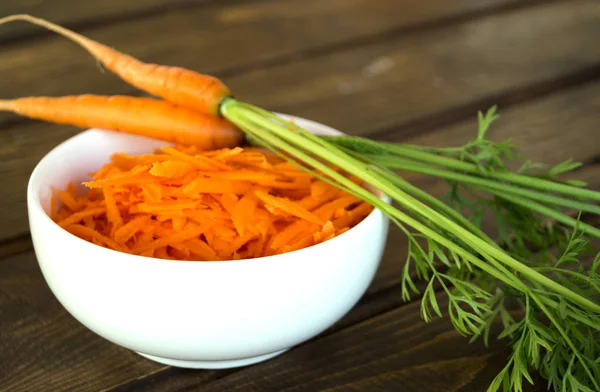 Carrot grated in a bowl, on a wooden table. — Stock Photo, Image