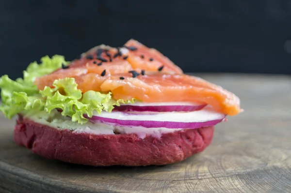 Red bun with lettuce, onion and salmon. — Stock Photo, Image