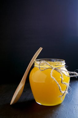 Bal arısı bir tahta kaşıkla bir kavanoz içinde.