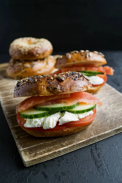 Bagels com creme de queijo e salmão defumado em um fundo preto — Fotografia de Stock