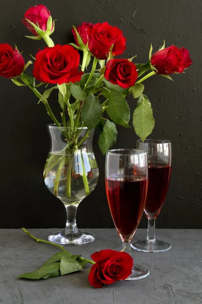 Roses and rose wine on a black background.