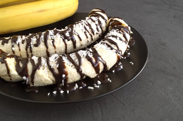 Bananas with chocolate and coconut chips on grey background. — Stock Photo, Image