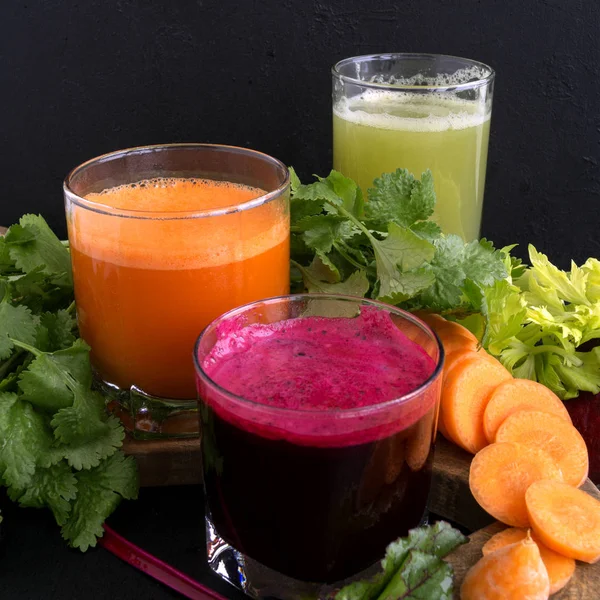 Vegetable juice in glass cups on a black background. Beets, cele — Stock Photo, Image