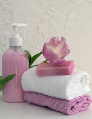 Sıvı sabun ve beyaz zemin üzerine iki havlu.