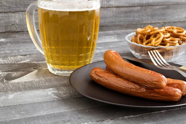 Embutidos a la parrilla con cerveza sobre una mesa de madera . — Foto de Stock