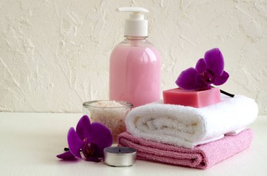 Sıvı sabun ve beyaz zemin üzerine iki havlu.