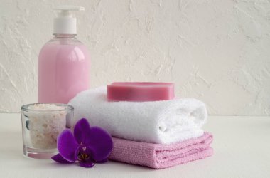 Sıvı sabun ve beyaz zemin üzerine iki havlu.