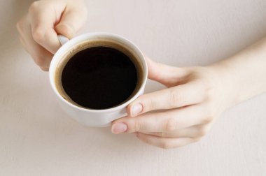 Bir fincan kahve parlak bir tabloda holding eller.