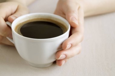 Bir fincan kahve parlak bir tabloda holding eller.